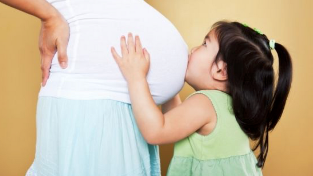 toddler girl kissing mom's belly